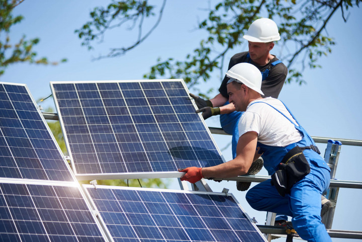Zwei Techniker montieren Solarpaneele bei sonnigem Wetter – Installation Erneuerbarer Energien