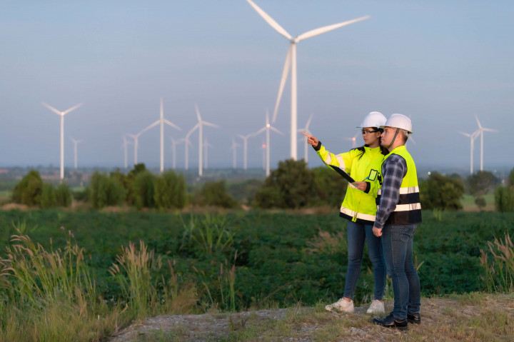 Zwei Fachkräfte in Schutzkleidung begutachten Windkraftstandort – Planungsarbeit