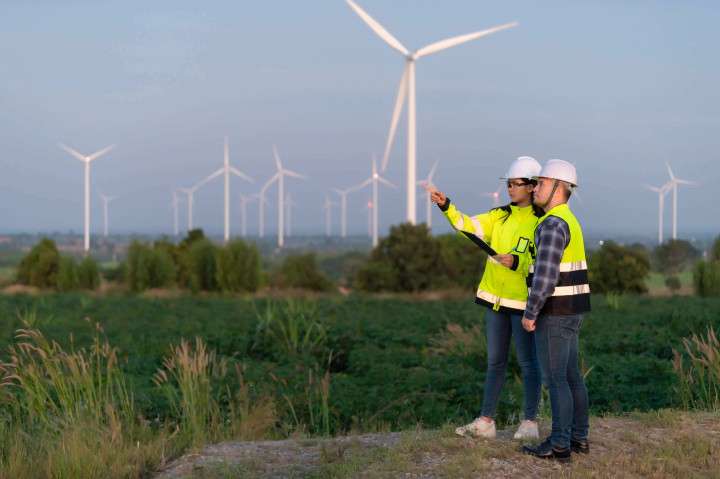Zwei Fachkräfte in Schutzkleidung begutachten Windkraftstandort – Planungsarbeit